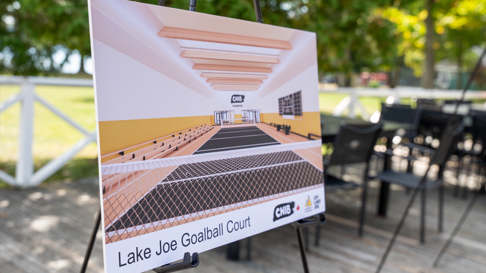 Représentation artistique du nouveau terrain de goalball du Camp Lake Joe d’INCA présentée sur un chevalet sur la terrasse du Camp Lake Joe d’INCA.