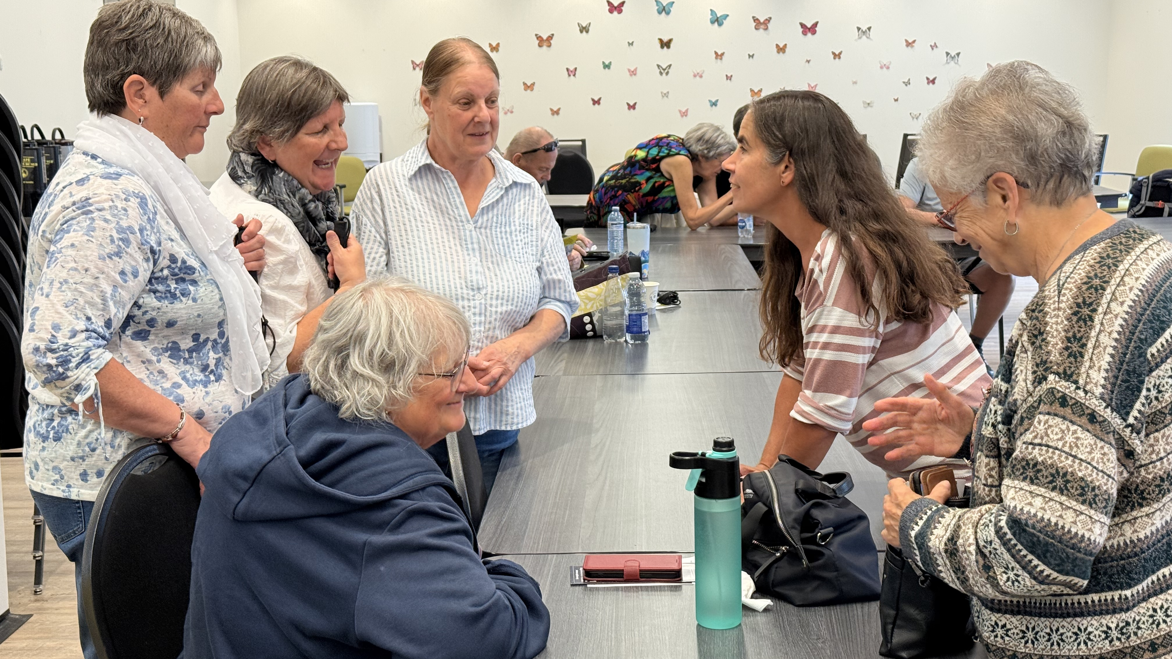 Lyne Dubé, chef de programme en technologie adaptée chez INCA, discute et rit avec cinq participantes.