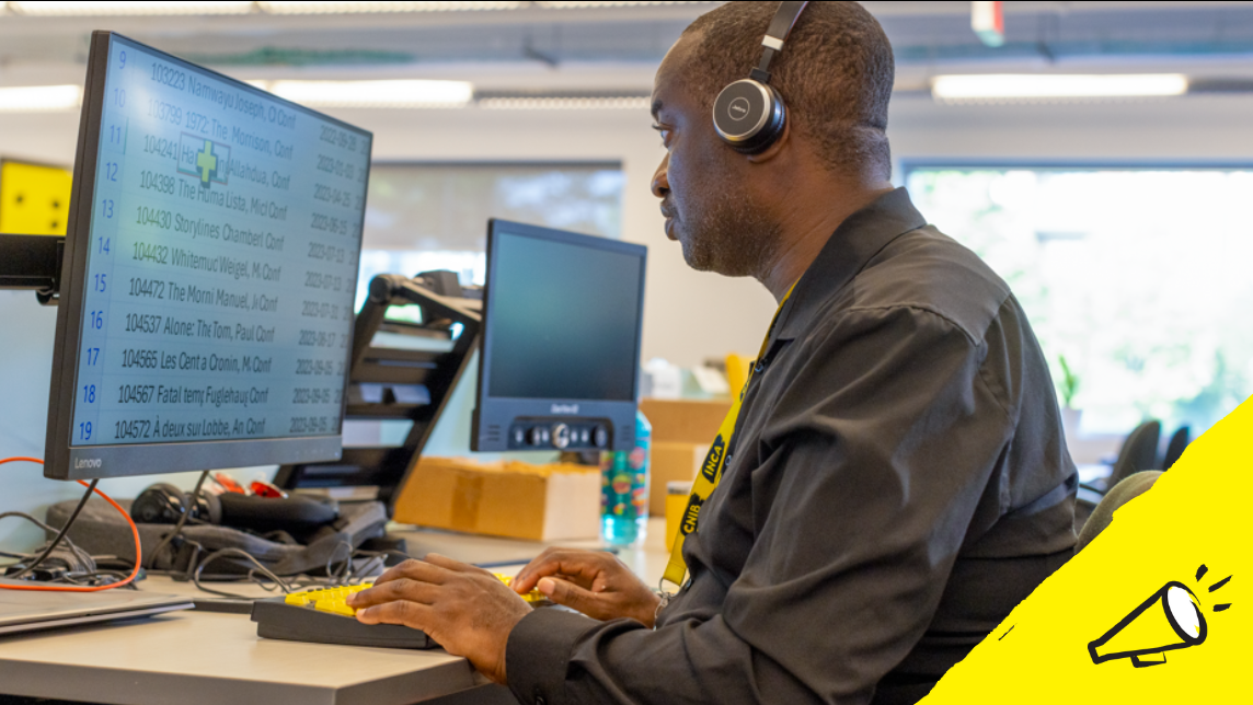 un homme est assis à un bureau et utilise une technologie d'agrandissement d'écran sur un ordinateur de bureau, ainsi qu'un clavier à contraste élevé.] 
