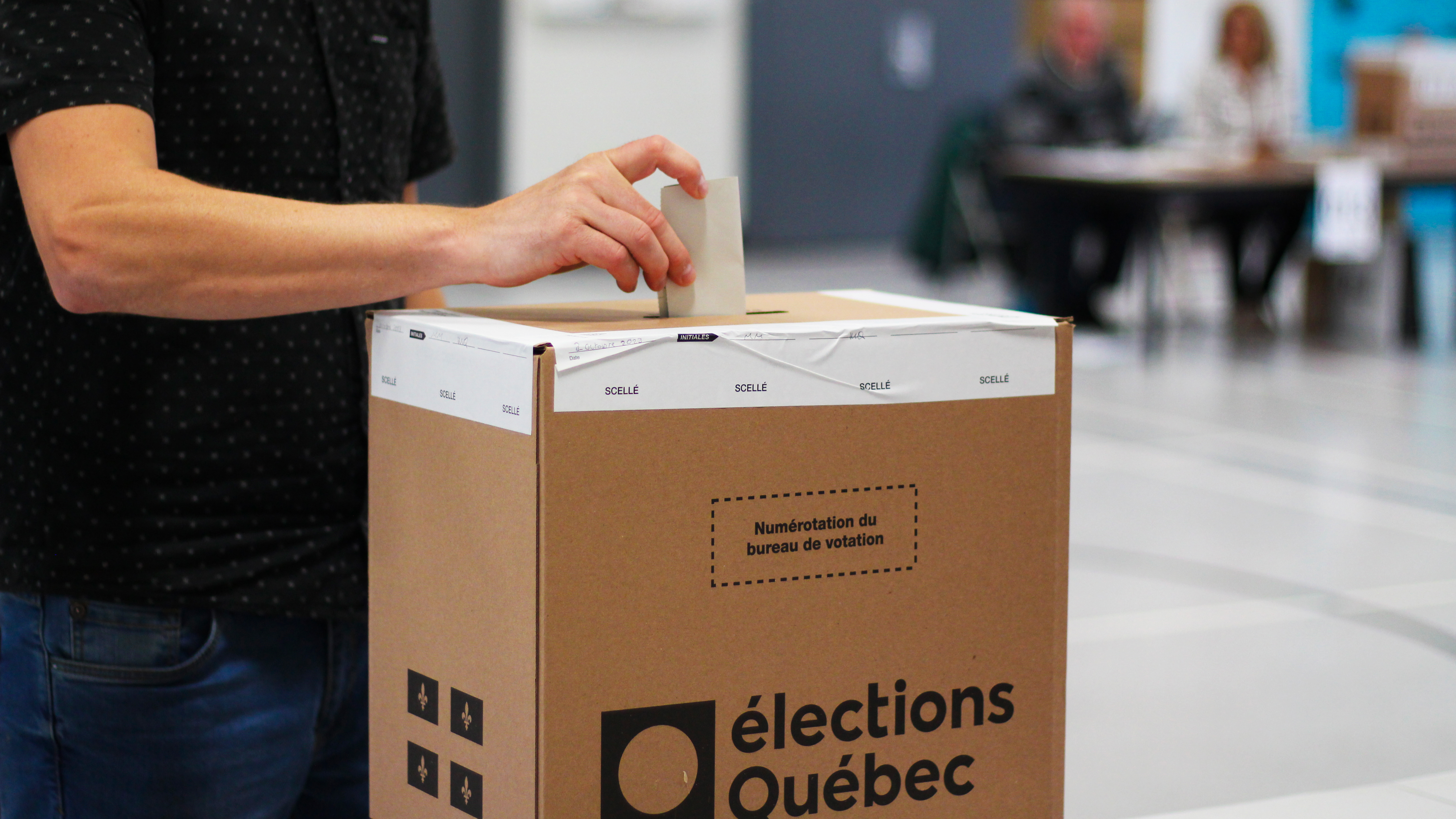 Un homme dépose son bulletin de vote dans une boîte d'Élections Québec