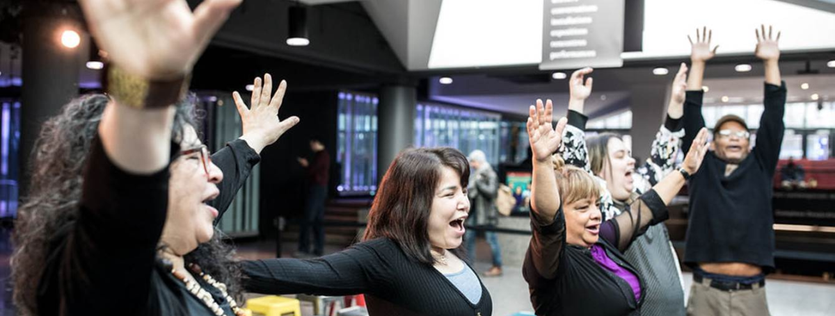 4 femmes et un homme les bras dans les airs chantent