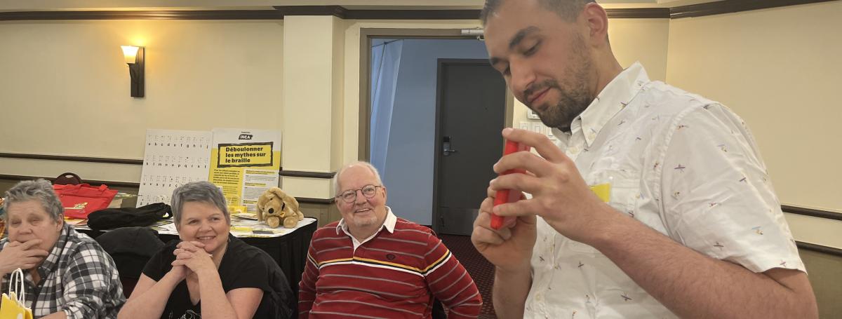 Mazen présente le téléphone Blindshell  devant des personnes souriantes et à attentives