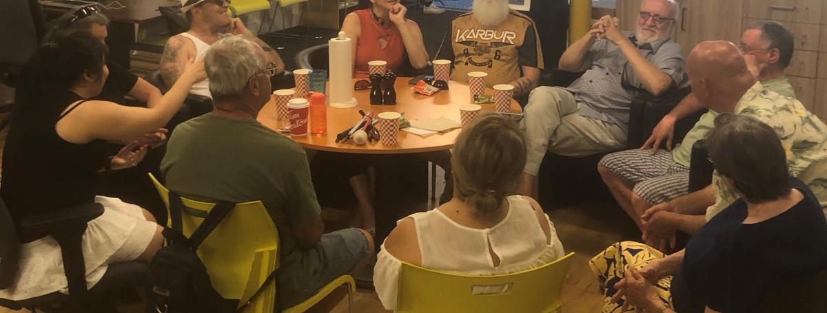 Groupe d'une dizaine de personnes confortablement assis autour d'une table à INCA discutant en souriant.