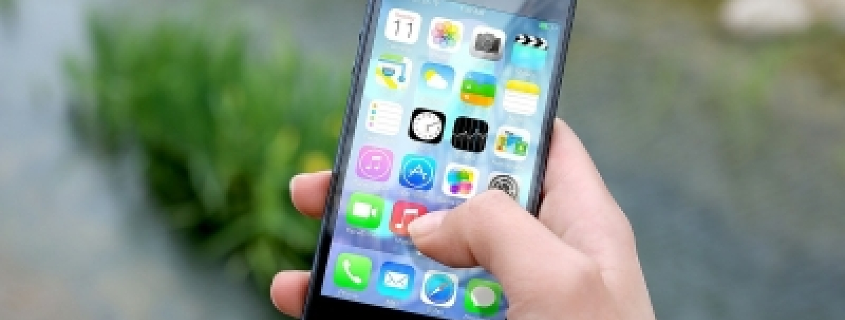 Une main tient un téléphone intelligent. On voit les icônes de plusieurs applications.  