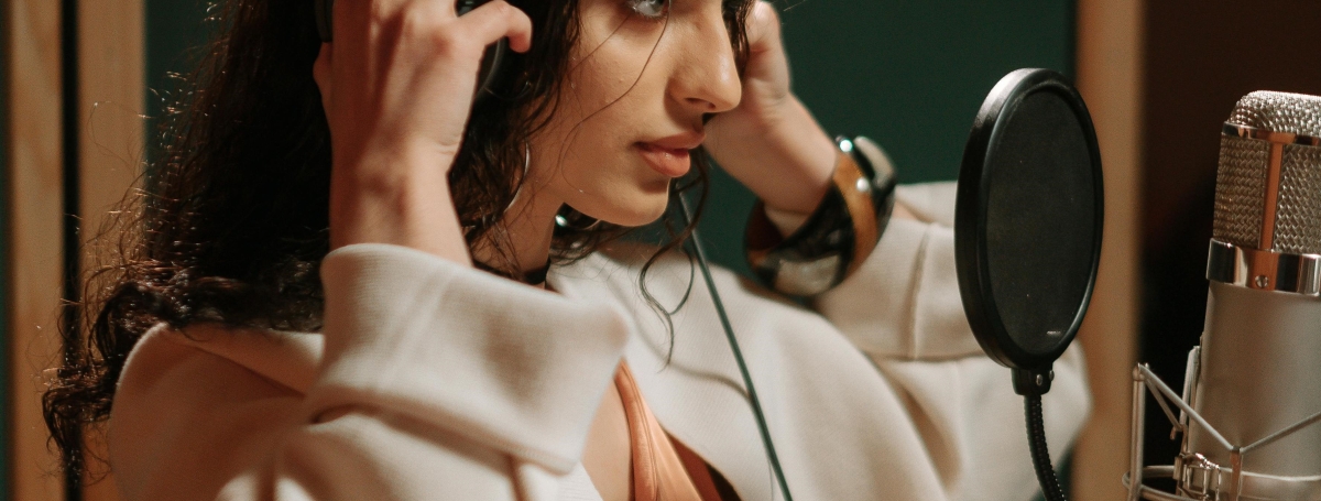 Une jeune femme porte un casque et enregistre un audio dans un studio