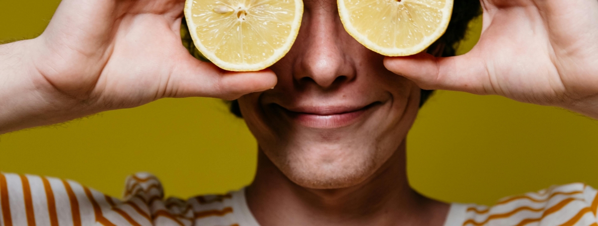 Un jeune homme tient deux citrons et les met devant ses yeux.