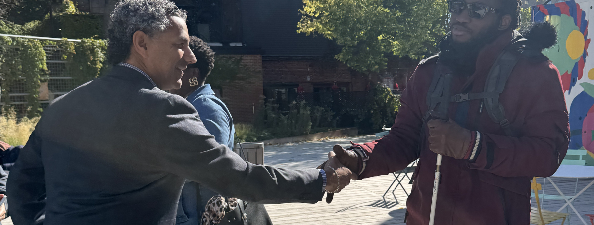 un candidat au municipal qui salue un homme en lunette noire et qui tient une canne blanche sur son autre main