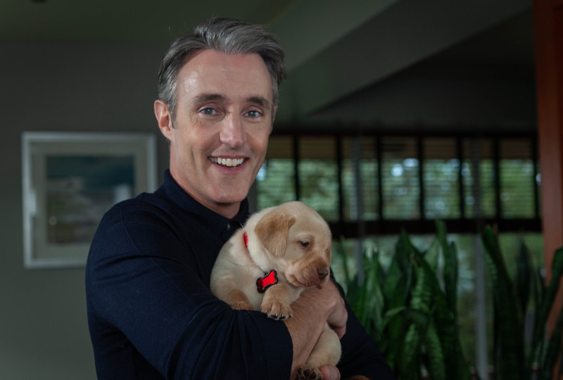 Ben Mulroney, ambassadeur de la marque INCA, tient un chiot dans ses bras
