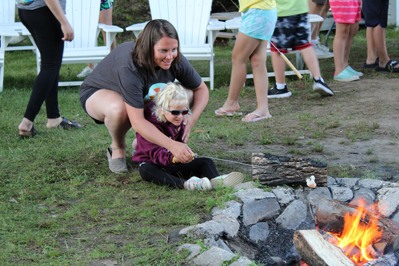 Un campeur et une jeune femme font griller une guimauve au-dessus d'un feu de camp.