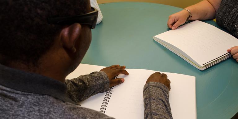 Man with sunglasses reading braille