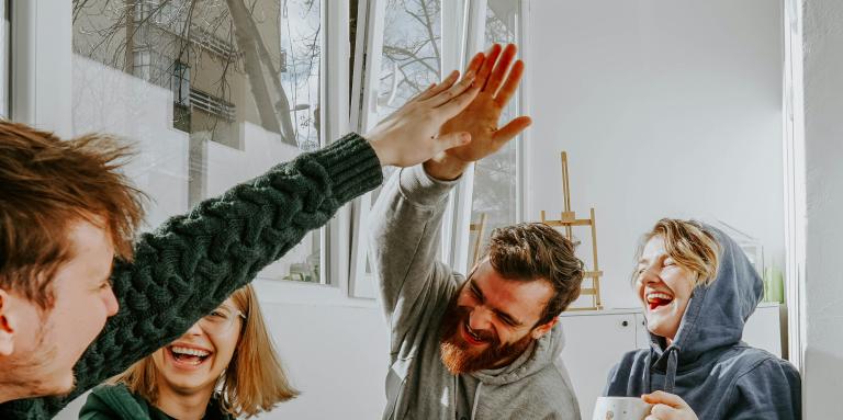 quatre jeunes qui rient avec leurs boissons chaudes dans un atmosphère décontracté