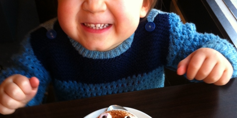 Un enfant en train de faire une grimace devant son chocolat chaud.