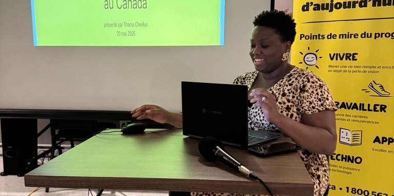 Thama assise derrière une ordinateur et un micro présente un Powerpoint.