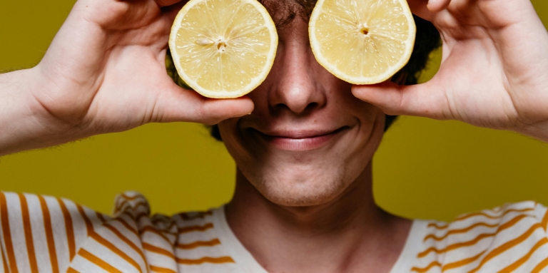 Un jeune homme tient deux citrons et les met devant ses yeux.