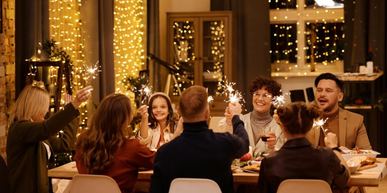 Une famille est à table et fête Noël. Pleins de guirlandes lumineuses sont accrochées aux fenêtres.