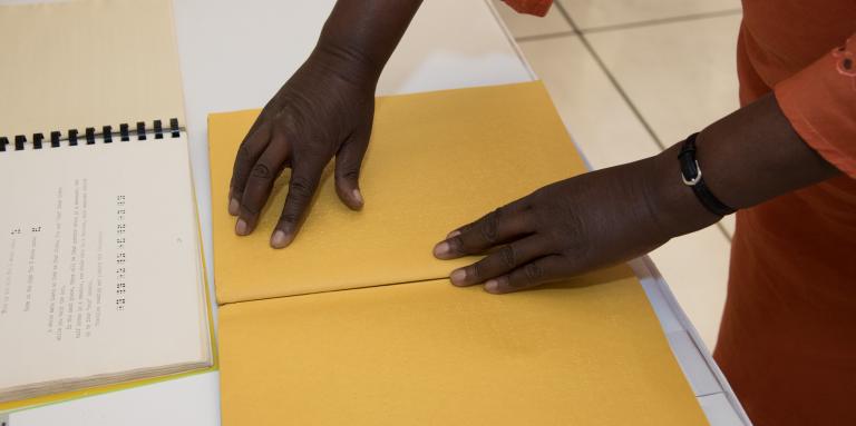 Hands over a braille book.