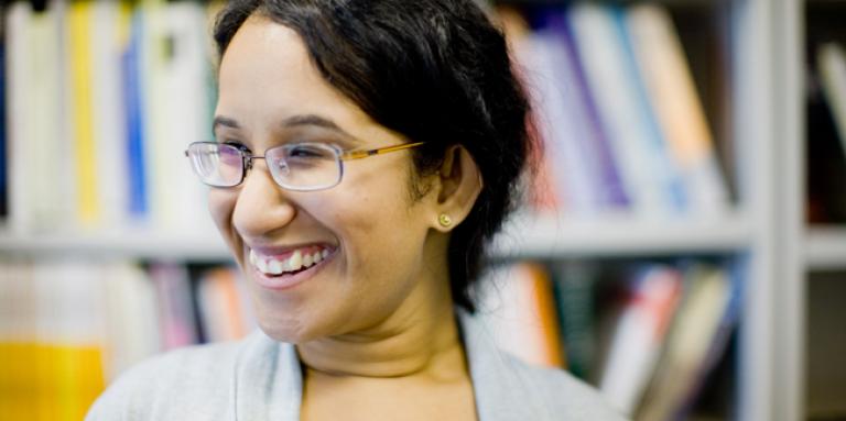 Head shot of a university-aged woman with library stacks behind her.