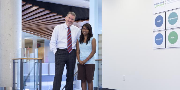 Older man and young woman standing next to each other in an empty hallway 