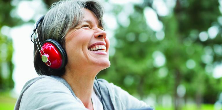 Woman sitting in a park listening to music through her phone and headphones