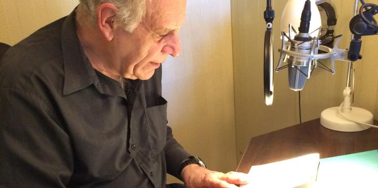 Pierre Germain lit un livre devant un micro