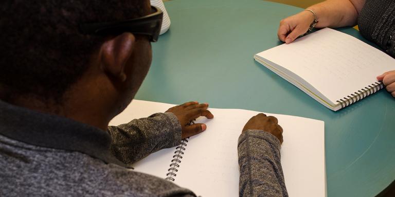 Man with sunglasses reading braille