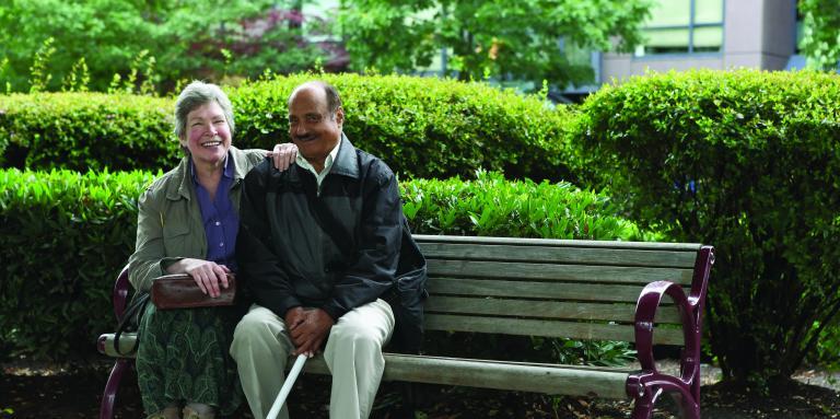 Homme avec une canne blanche et une femme assise sur un banc