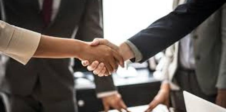 Two women shake hands in an office.