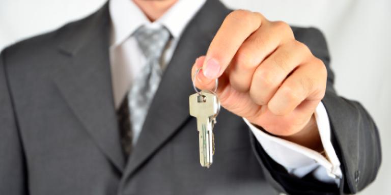 man in suit holding a set of keys