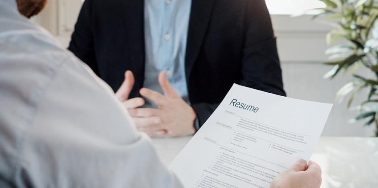 Un recruteur tient un CV et interviewe un candidat.