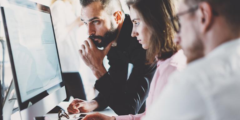 Two men and a women looking at a computer screen