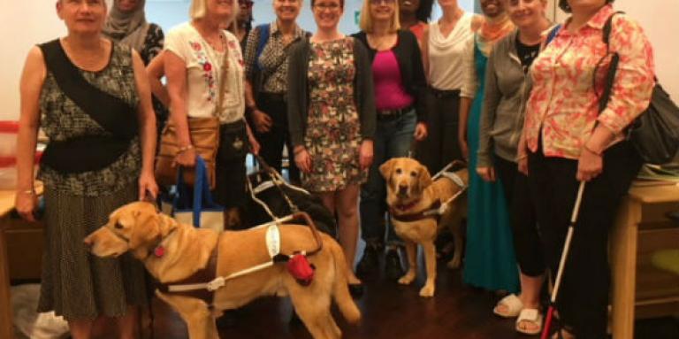 Groupe de personnes avec cannes et chiens-guides souriant pour l’appareil photo. 