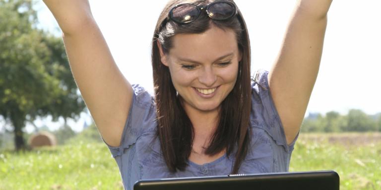 Photo d'une femme bras en l'air devant son ordinateur