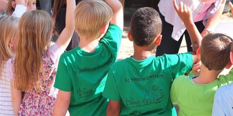  Un groupe de jeunes enfants lève les mains en l'air pour répondre à une question.