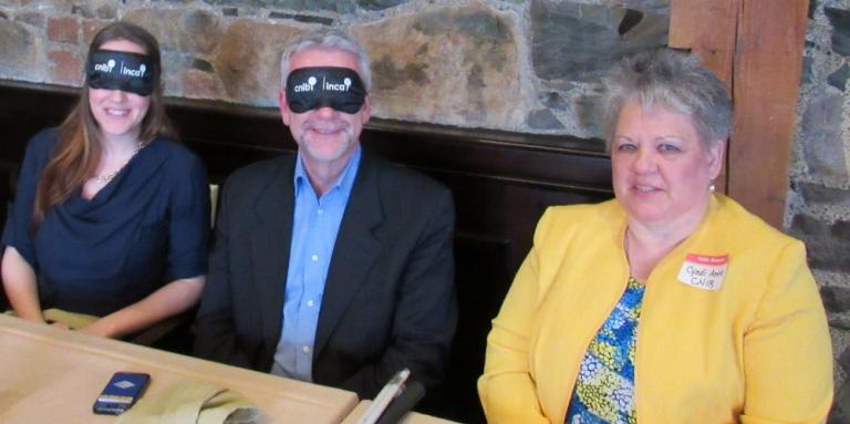 De droite à gauche : Cindy Antle avec M. Danny Breen, le maire de St. John's et Mme Amanda Mews de NTV portant tous deux un bandeau utilisé lors des Soupers dans le noir d'INCA