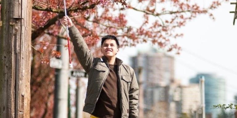 Un jeune homme tient sa canne blanche dans les airs triomphalement.