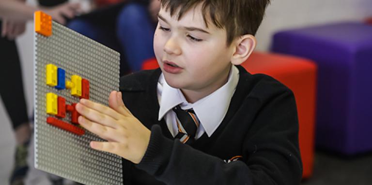 Un garçon joue avec des briques LEGO en braille  