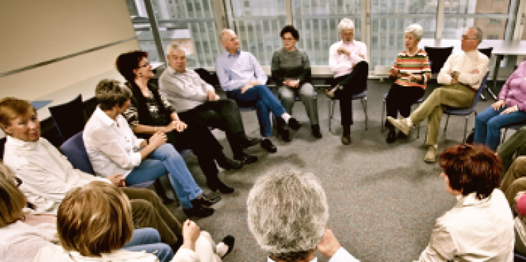 Un grand groupe de 17 personnes se réunit dans un groupe de soutien. Ils sont assis en cercle.