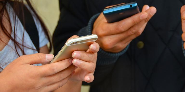 Deux paires de mains tenant un iPhone.