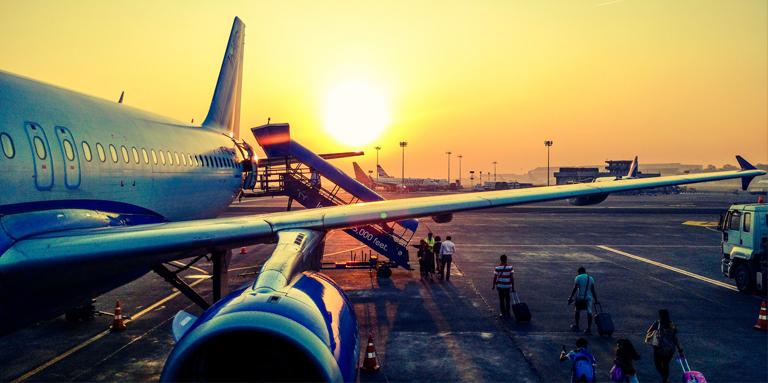 People boarding an airplane at sunset.