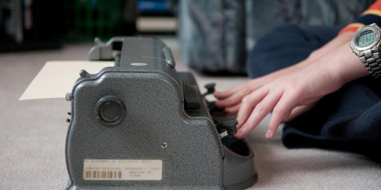 Des mains tapant sur une machine à écrire en braille.