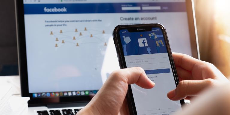 Une page Facebook est ouverte sur l'écran d'un ordinateur portable et d'un téléphone intelligent.