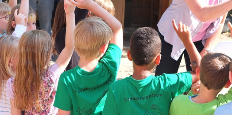 Un groupe de jeunes enfants lève les mains en l'air pour répondre à une question