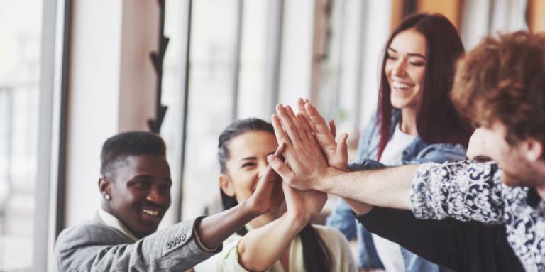 Un groupe d’entrepreneurs se faisant des «high-fives» à un bureau.