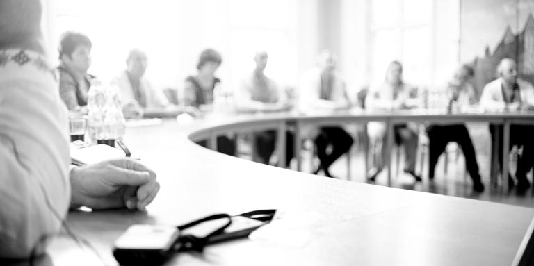 A black & white photograph of people at a round table discussing different issues.