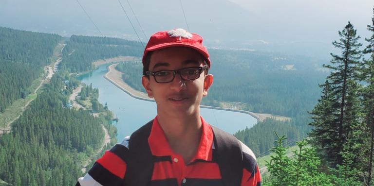 Un jeune homme pose pour une photo devant des montagnes pittoresques. 