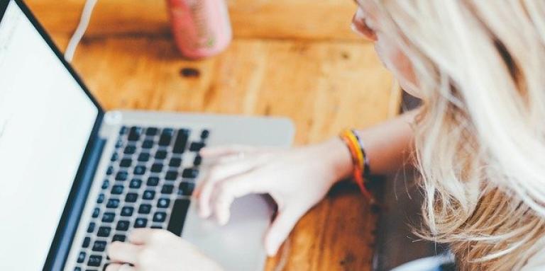 Une jeune femme est assise devant un ordinateur portable et étudie.