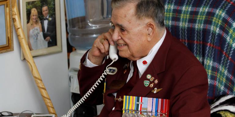 Un homme âgé sourit en parlant au téléphone.  