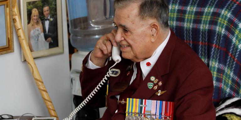 Un homme âgé sourit en parlant au téléphone.  