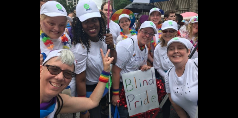 Des participants, des employés et des bénévoles d'INCA arborant des tee-shirts blancs, des casquettes de baseball et des sourires lors du défilé de la Fierté de Toronto