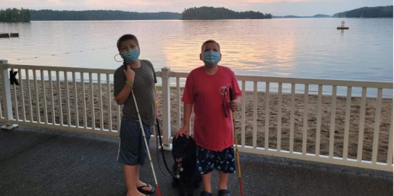 Mason (à gauche), Ollie (à droite) et le chien compagnon Hope posent pour une photo au camp Lake Joe. Ils portent chacun un masque et tiennent chacun leur canne blanche